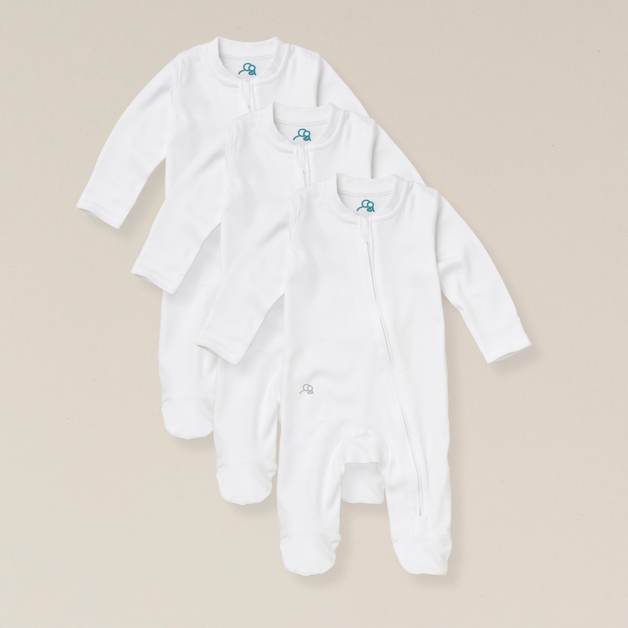 Three white baby onesies with a small logo on a beige background