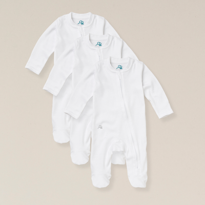 Three white baby onesies with a small logo on a beige background