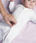 Young baby in white sleepsuit with head to toe zip
